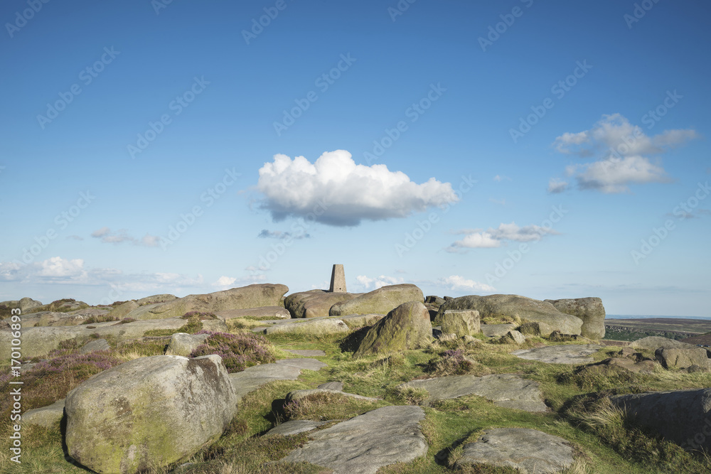 Summer landscape image of trig point on top of Stanage Edge in Peak District