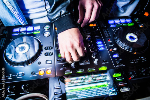 detail of a dj's hands mxing on the console in a disco