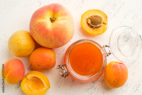 homemade jam of ripe peaches on a white wooden background