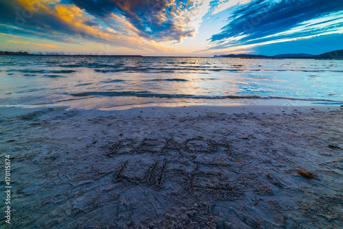 Beach life written on the sand at sunset