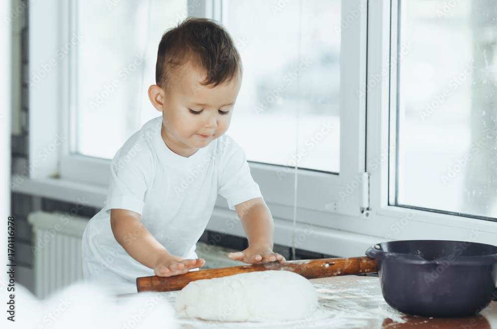 A child with a rolling pin at the table A child with a rolling pin at the table