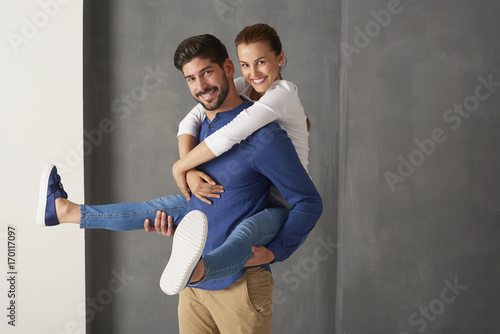 Shot of a young couple having fun. Smiling handsome man giving piggyback to her smiling girlfriend.