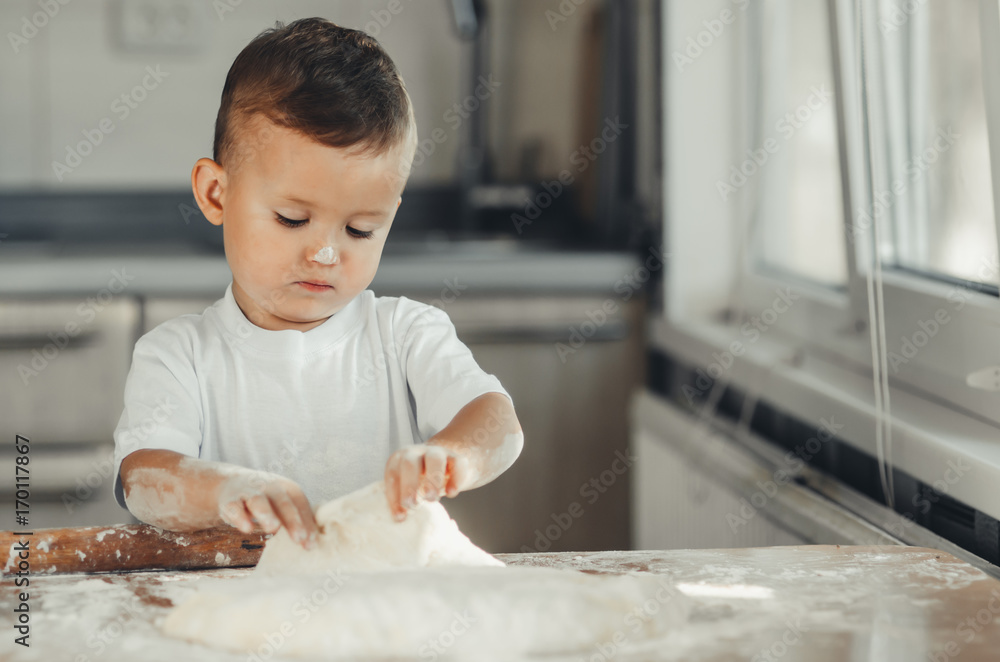 Fototapeta premium A child with a rolling pin at the table