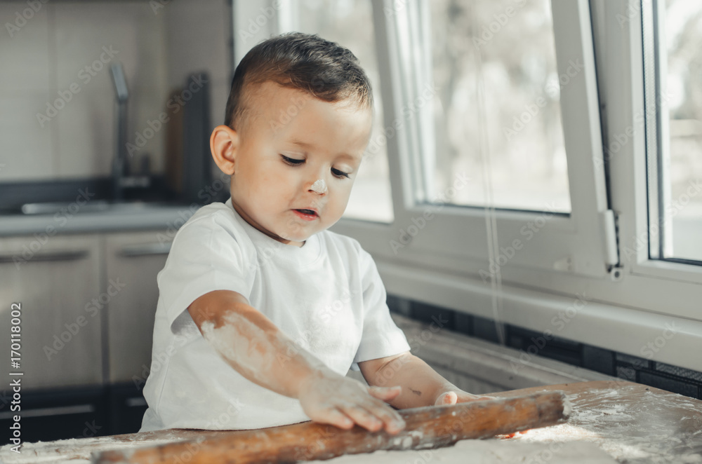 Fototapeta premium A child with a rolling pin at the table