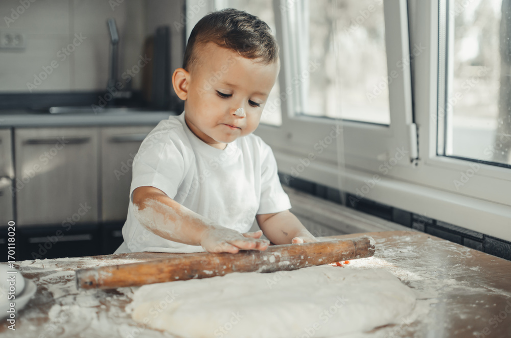 Fototapeta premium A child with a rolling pin at the table