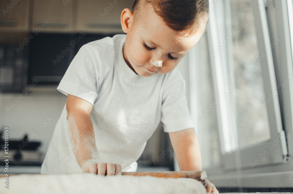 A child with a rolling pin at the table A child with a rolling pin at the table