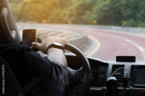 Man's hand on the steering wheel inside of a car, selective focus