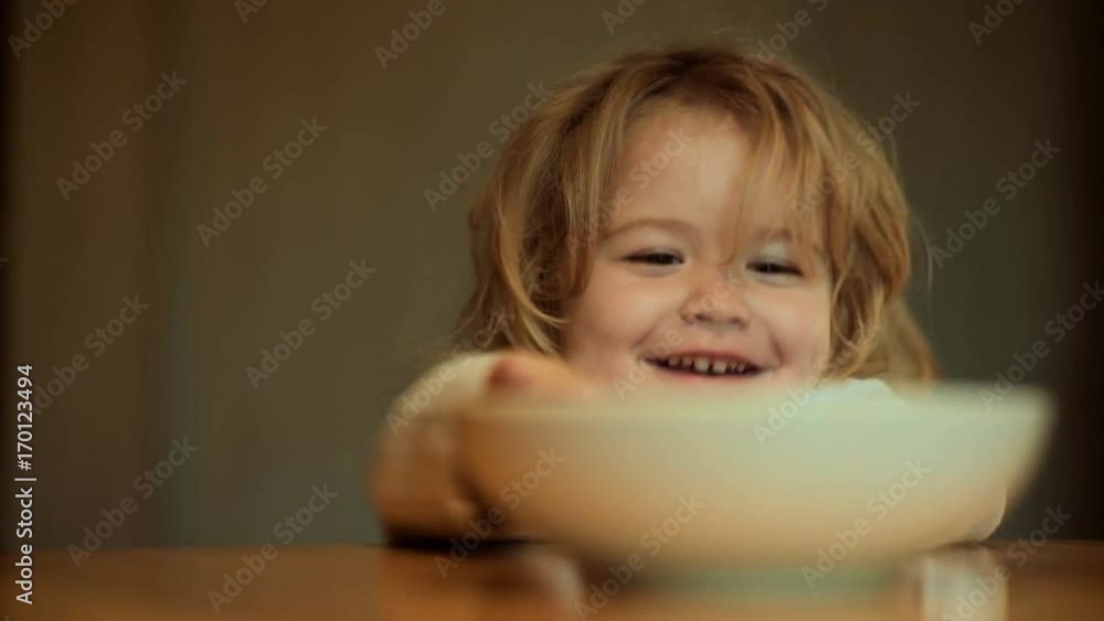 Funny child food playing in kitchen. Child does not want to eat. Baby food and lack of appetite. Cheerful game with plate in kitchen table. Cute boy long hair breakfasts with father, toddler breakfast Funny child food playing in kitchen. Child does not want to eat. Baby food and lack of appetite. Cheerful game with plate in kitchen table. Cute boy long hair breakfasts with father, toddler breakfast
