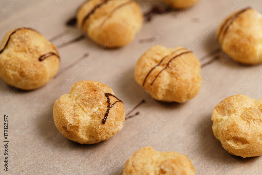 profiteroles decorated with dark chocolate on brown paper closeup
