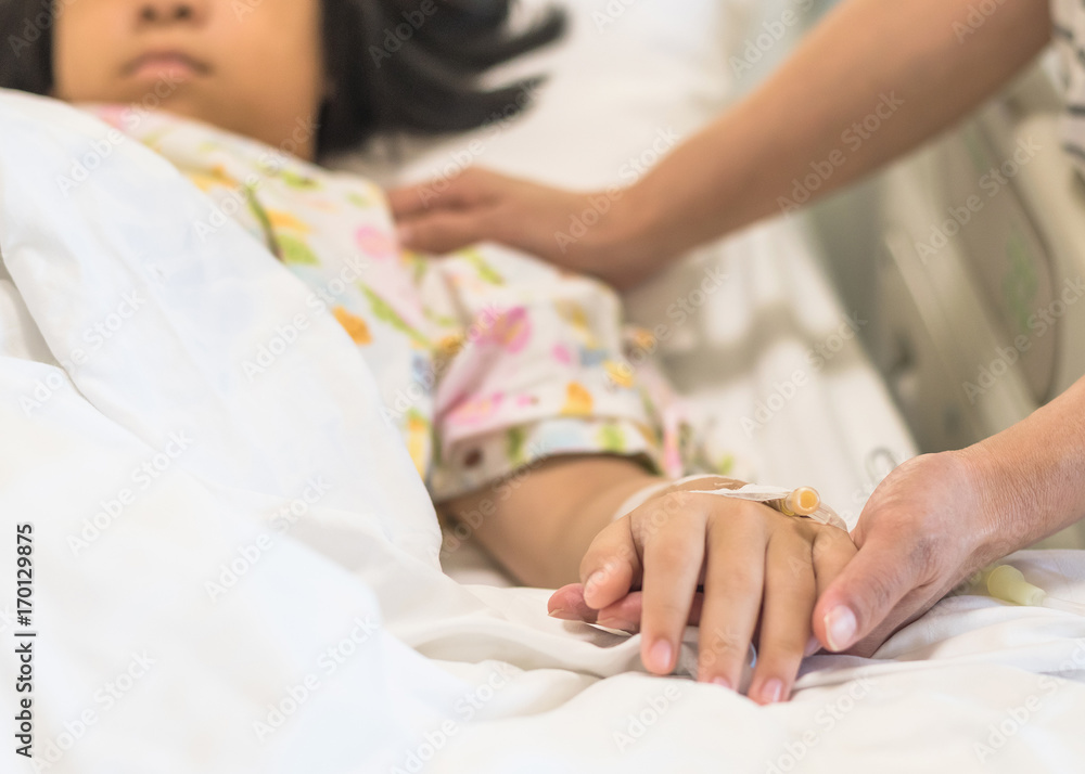 Nursing caretaker concept with kid patient sleeping in bed with family caregiver hand support in blur medical hospital background (focus on hand) Nursing caretaker concept with kid patient sleeping in bed with family caregiver hand support in blur medical hospital background (focus on hand)