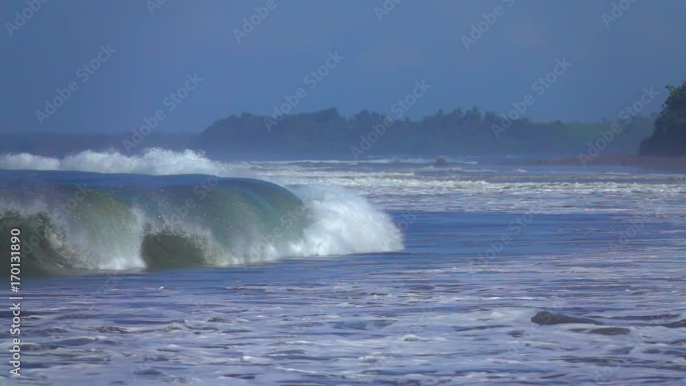 SLOW MOTION CLOSE UP: Big barrel wave crashing on shallow sandbars in the ocean. Huge tropical tube wave breaking and splashing water drops. Surf sea wave rolling towards the Bali beach and collapsing SLOW MOTION CLOSE UP: Big barrel wave crashing on shallow sandbars in the ocean. Huge tropical tube wave breaking and splashing water drops. Surf sea wave rolling towards the Bali beach and collapsing