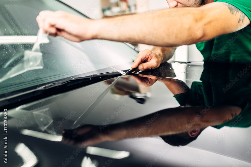 Obraz premium Man installs car paint protection film on hood