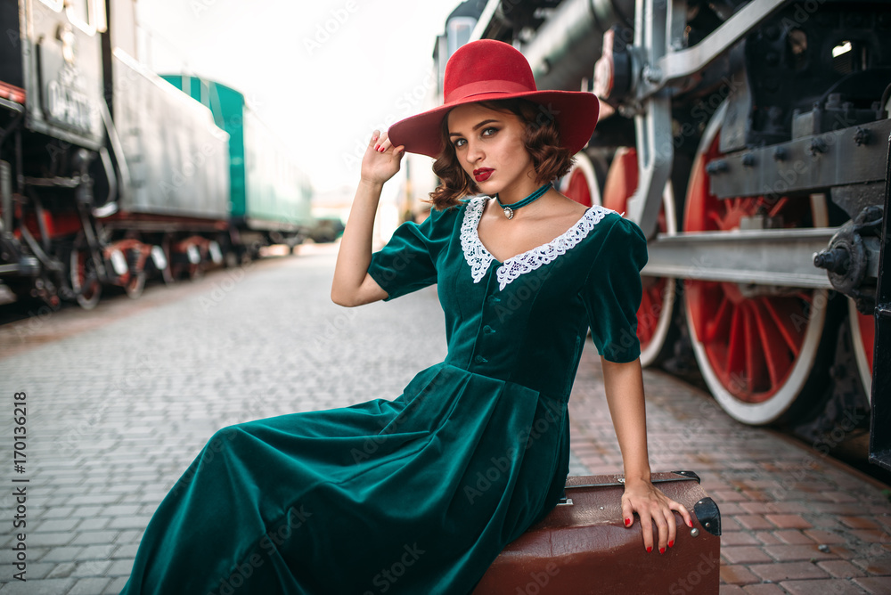 Woman in red hat against vintage steam train
