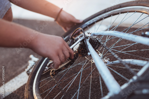 Teenager boy repair tire on bicycle summer outdoor photo, close up