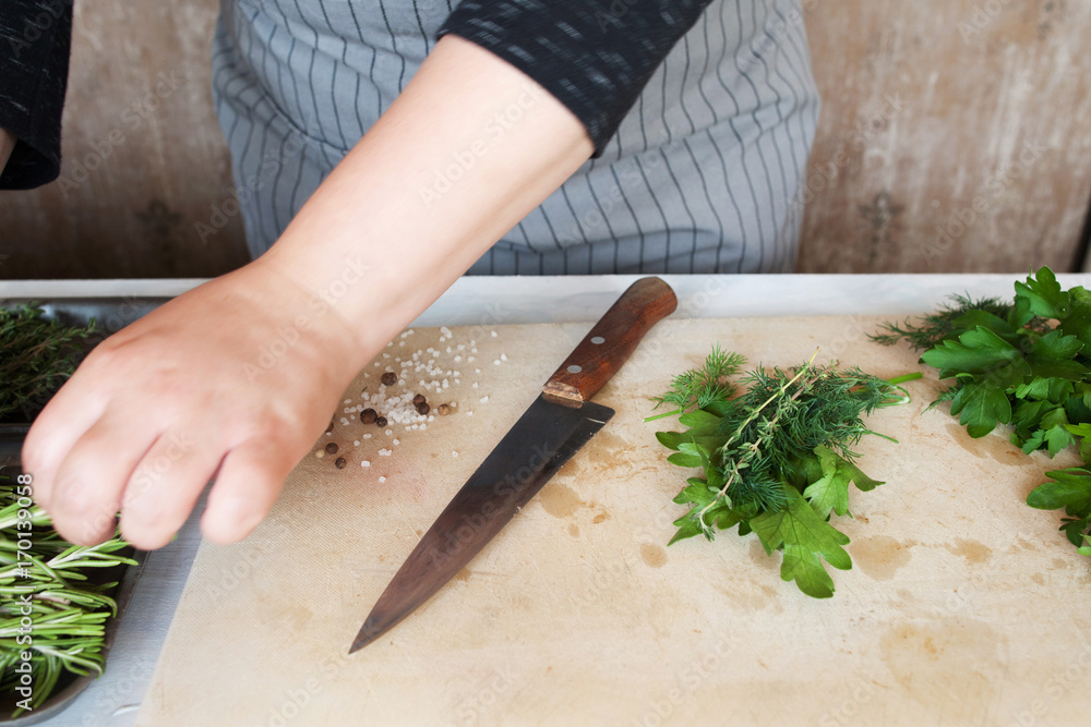 Cook preparing green herbs on wooden desk. Cooking process, healthy organic food and decoration, close up picture Cook preparing green herbs on wooden desk. Cooking process, healthy organic food and decoration, close up picture