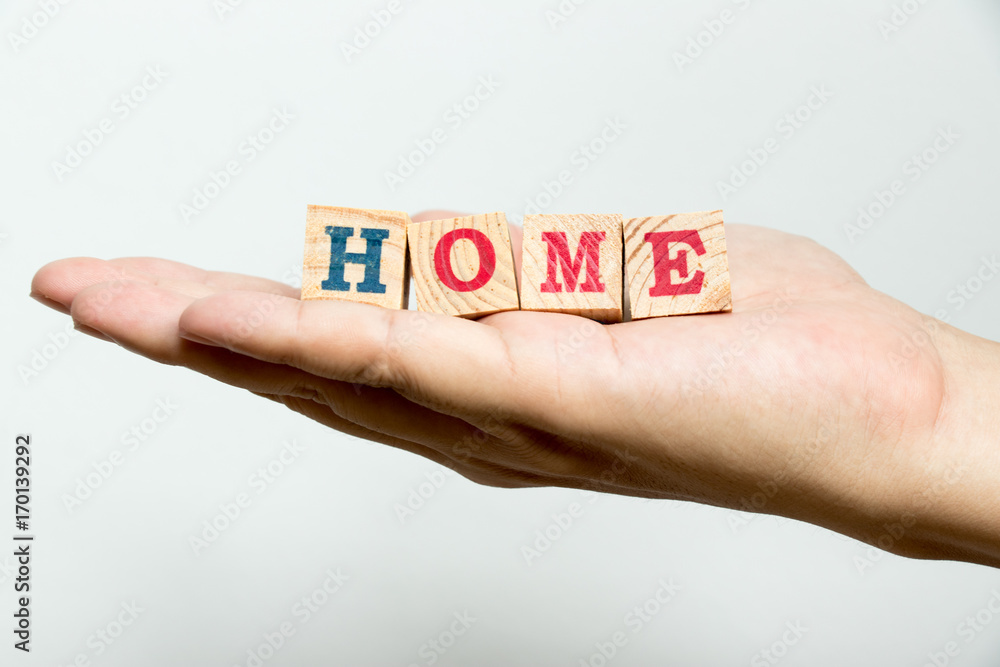 Man hold wood block with wording home on concrete background Man hold wood block with wording home on concrete background