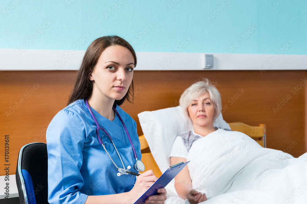 Obraz premium Portrait of attractive female doctor in uniform writing down complaints of patient