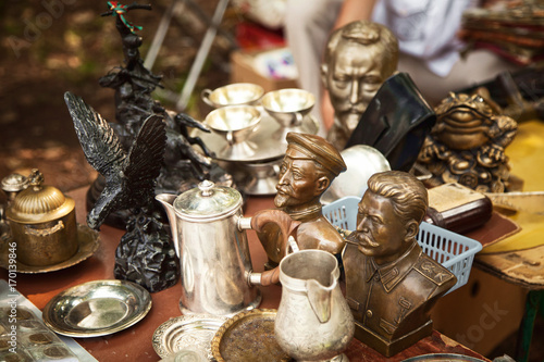USSR famous historic persons busts and metal tableware at a flea market. Many old vintage things at a garage sale