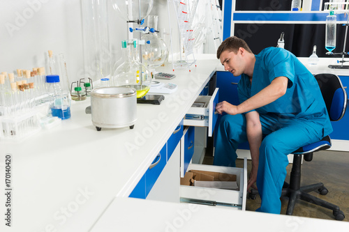 Scientist in uniform is .looking for something in a cases in a laboratory