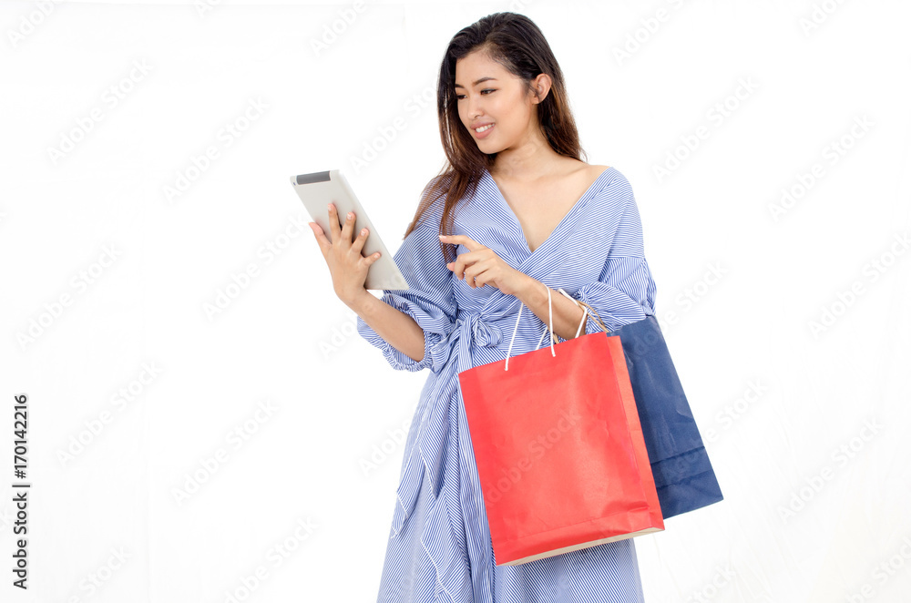 cheerful asian young woman holding shopping bags and holding tablet in hand isolated on white background, lifestyle smart communication technology, online shopping and payment online concept cheerful asian young woman holding shopping bags and holding tablet in hand isolated on white background, lifestyle smart communication technology, online shopping and payment online concept