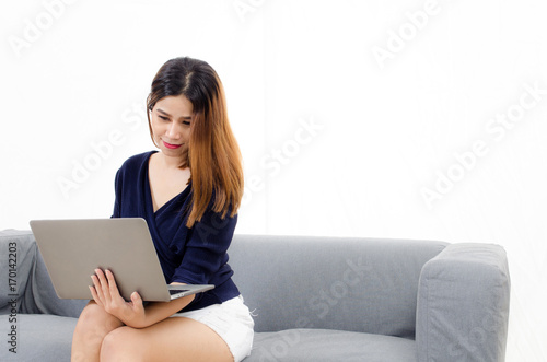 happy beautiful young asian woman using laptop computer on on sofa at home on white background, soft focus, lifestyle smart communication technology, online shopping and payment online concept
