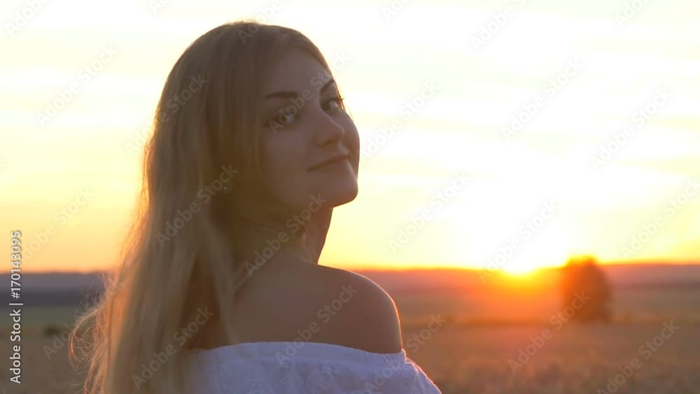 Face of a young beautiful girl in a wheat field at sunset in the sun. A happy look and a smile on my face Face of a young beautiful girl in a wheat field at sunset in the sun. A happy look and a smile on my face