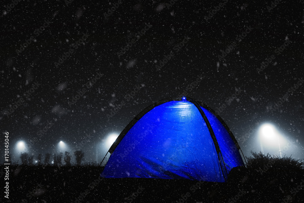 Blue tent with light in the winter snow.