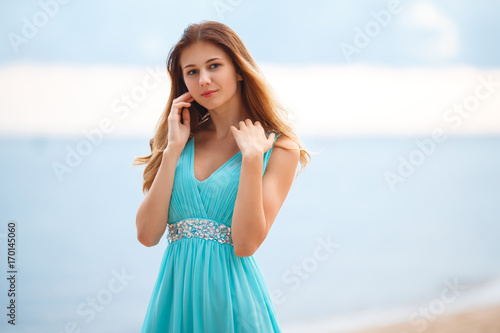 Beautiful young girl in a light blue dress on the beach 