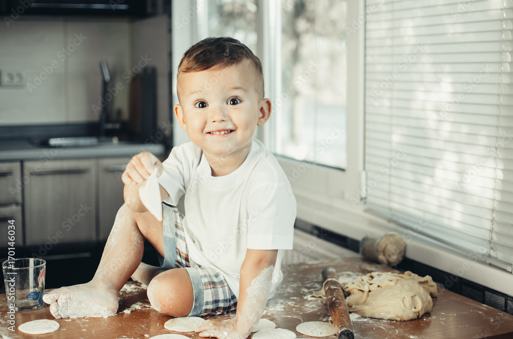 Fototapeta premium A small child sitting on a table covered in flour