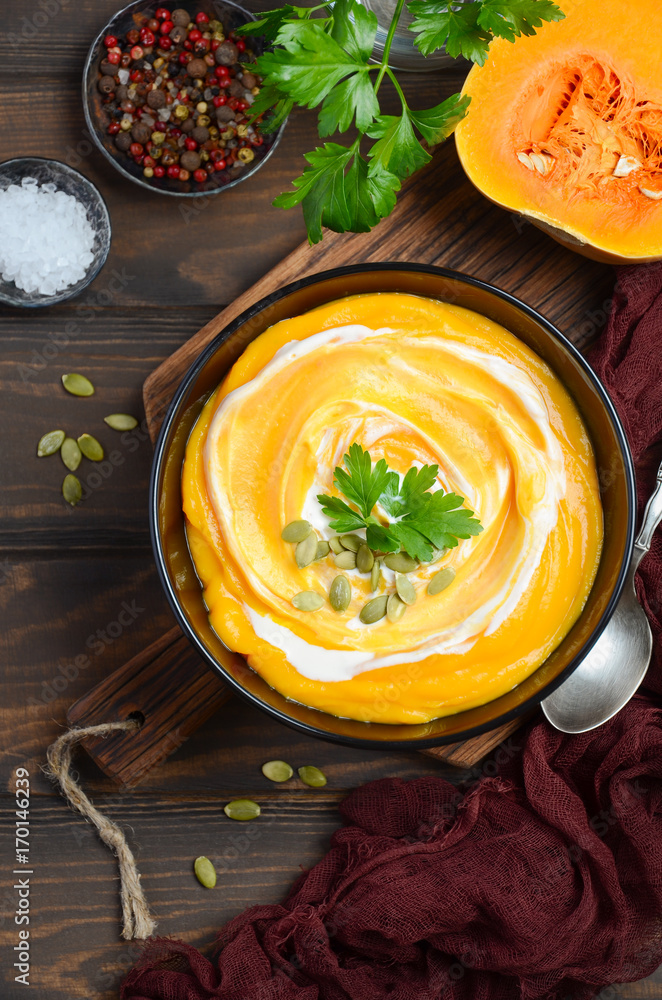 Pumpkin cream soup with cream and pumpkin seeds on wooden background, top view Pumpkin cream soup with cream and pumpkin seeds on wooden background, top view