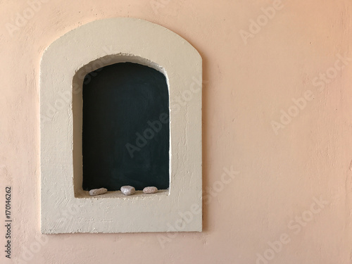 A little recess with arch, shells and black background on a pale pink wall. Copy space.