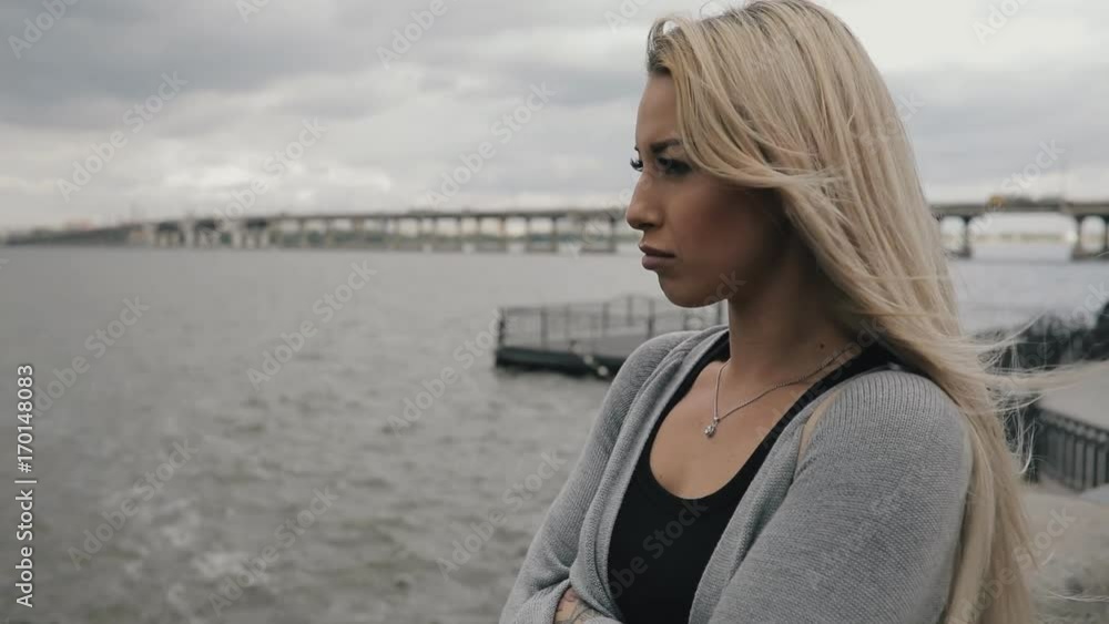 Autumn is coming. Woman near river, the wind blows her hair, autumn cold cloudy day. Autumn is coming. Woman near river, the wind blows her hair, autumn cold cloudy day.