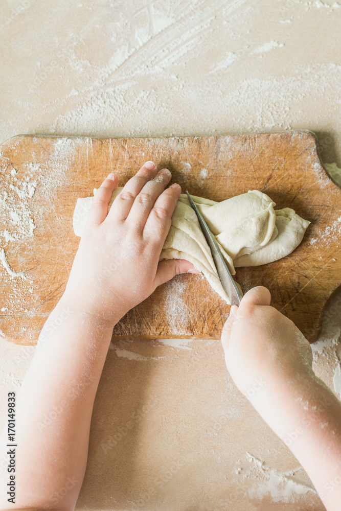 Fototapeta premium A child cuts the raw dough