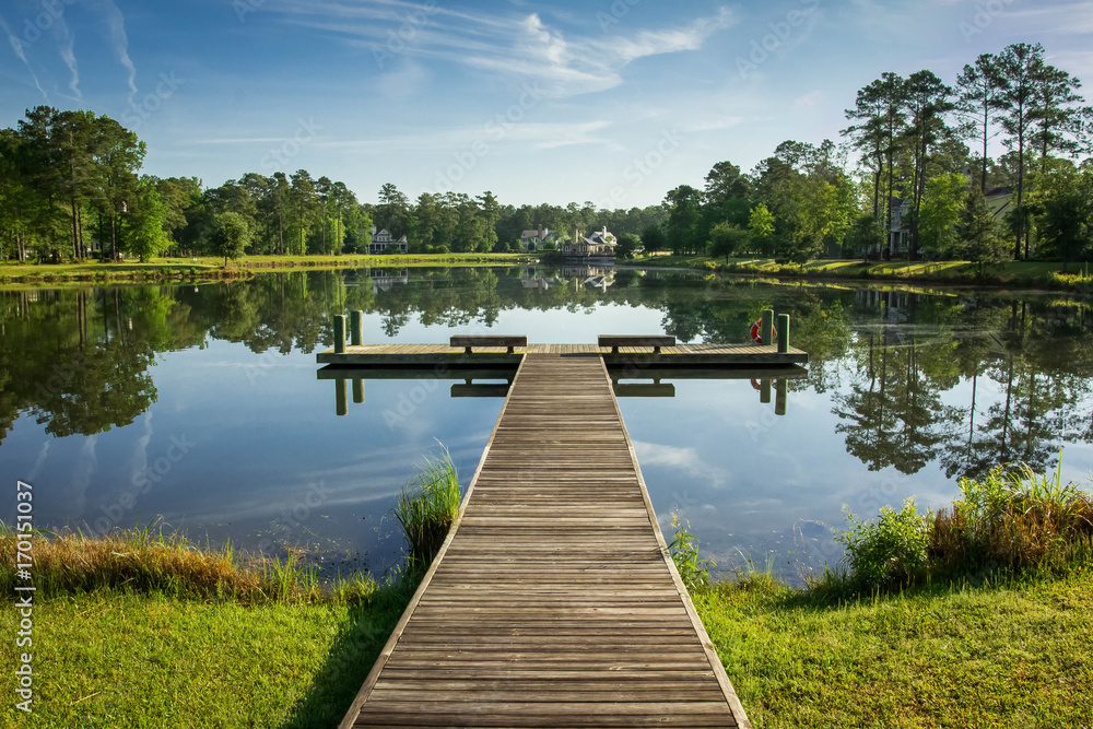 Obraz premium molo nad spokojnym jeziorem lub stawem z błękitnym niebem i refleksją