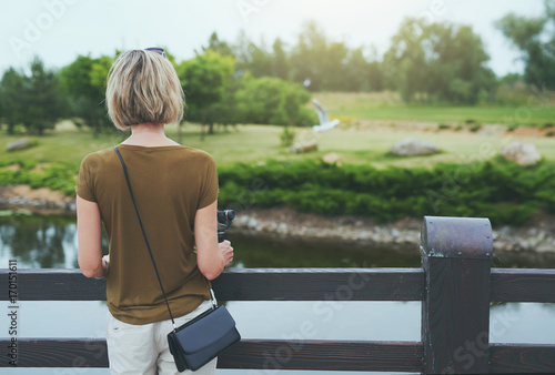 Woman enjoying view in a park, holding small personal camera in hands