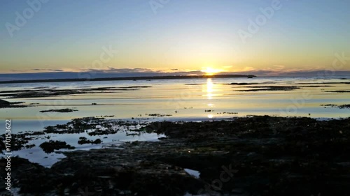 Blue and purple sunset in Rimouski, Quebec by Saint Lawrence river in Gaspesie region of Canada with closeup of water shore and waves photo