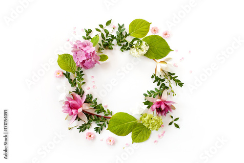 creative floral arrangement. round frame with blooming flowers, leaves and petals on white background. flat lay, top view