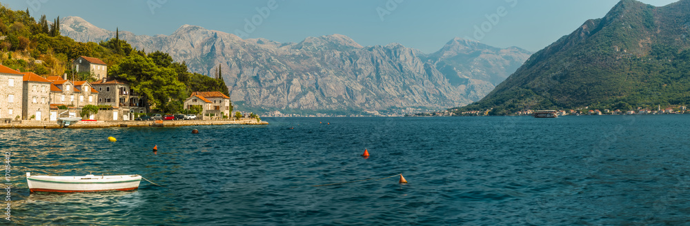 Panorama of Boka-Kotorsky Bay with a fragment of the embankment of the ancient city of Perast, Montenegro. A view of the mountains from the waters of the Bay of Kotor on the Adriatic Sea.