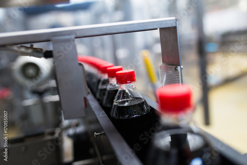 Bottling factory - Black juice or soft drink bottling line for processing and bottling juice into bottles. Selective focus. 