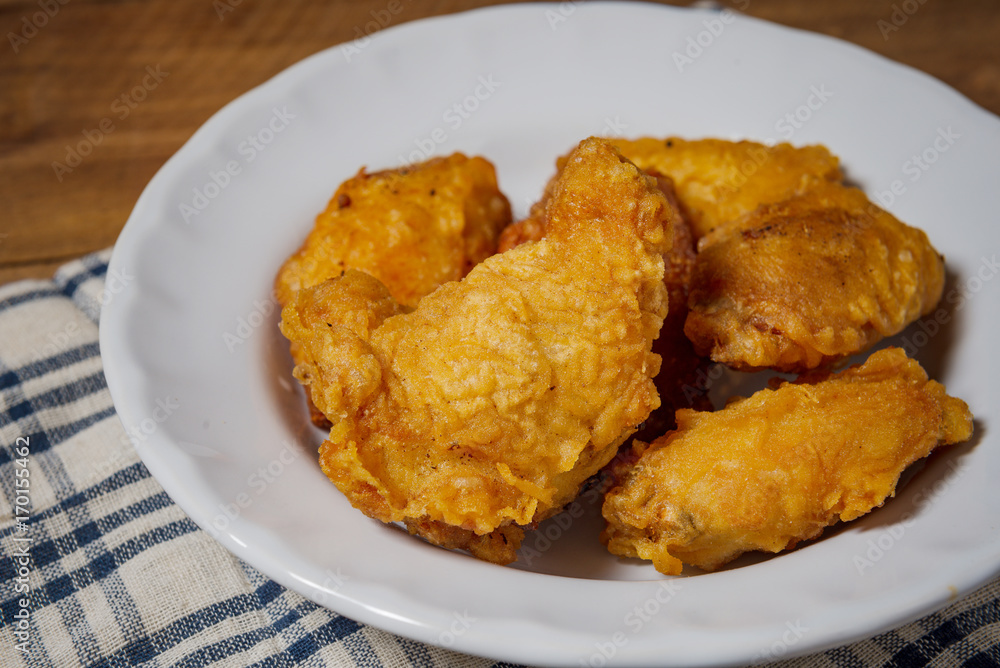 Fried chicken wings on a white plate, on a wooden table. Fried chicken wings on a white plate, on a wooden table.