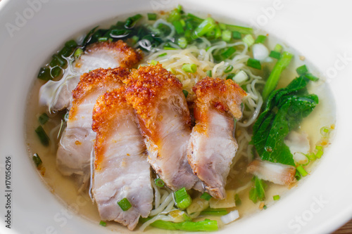 Delicious Thai egg noodles topped with crispy roasted pork on wooden background