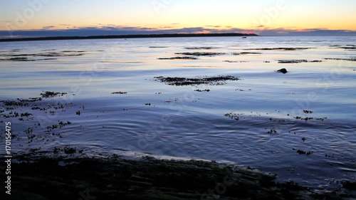 Blue, purple and red sunset twilight in Rimouski, Quebec by Saint Lawrence river in Gaspesie region of Canada with closeup of waves photo