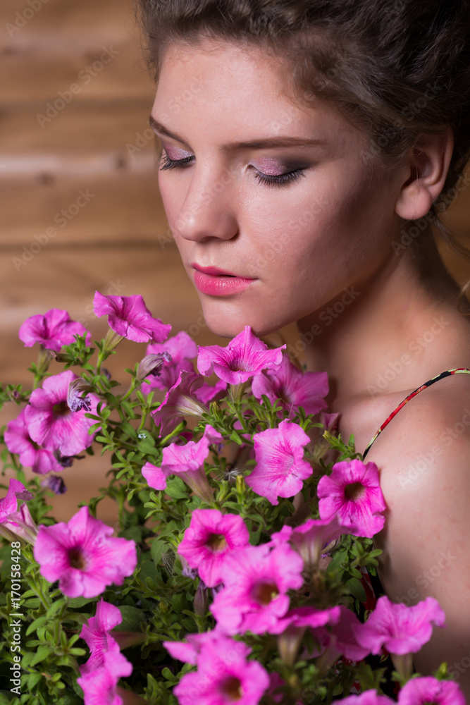 Naklejka premium Beautiful young woman holding a pot of ampel Petunia flowers
