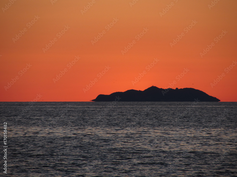 Beautiful sea sunset with island silhouette panorama . View of Gorgona island from Livorno city . Tuscany, Italy
