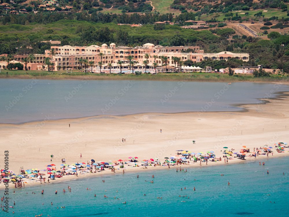 The sandy beach of Porto Giunco in Sardinia between the blue sea and the pond of Notteri famous for its pink flamingos. The sandy beach of Porto Giunco in Sardinia between the blue sea and the pond of Notteri famous for its pink flamingos.