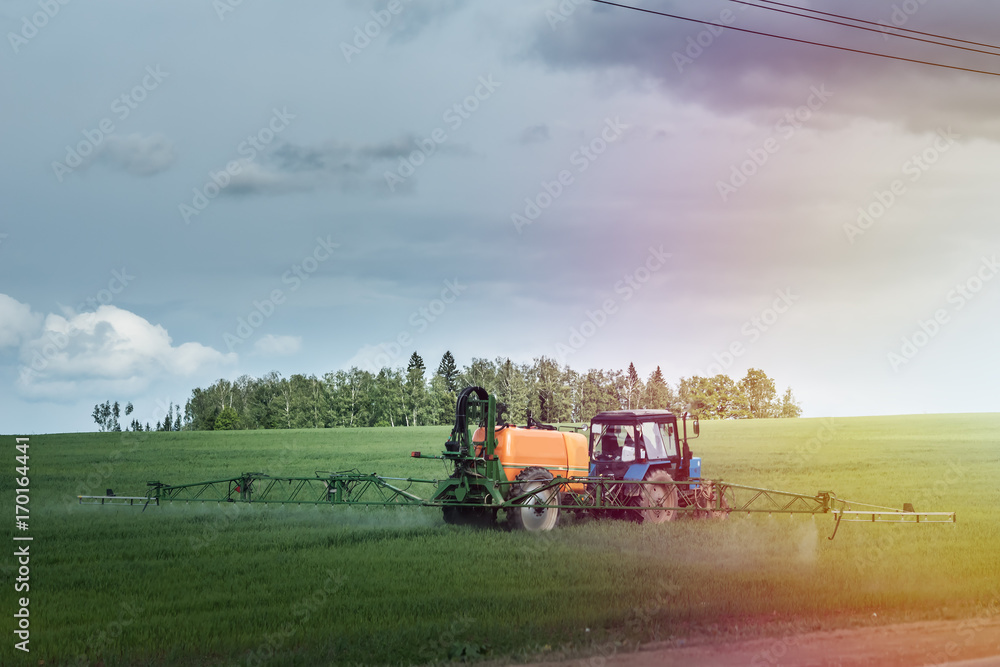 Fototapeta premium Farm machinery spraying insecticide to the green field, agricultural natural seasonal spring background