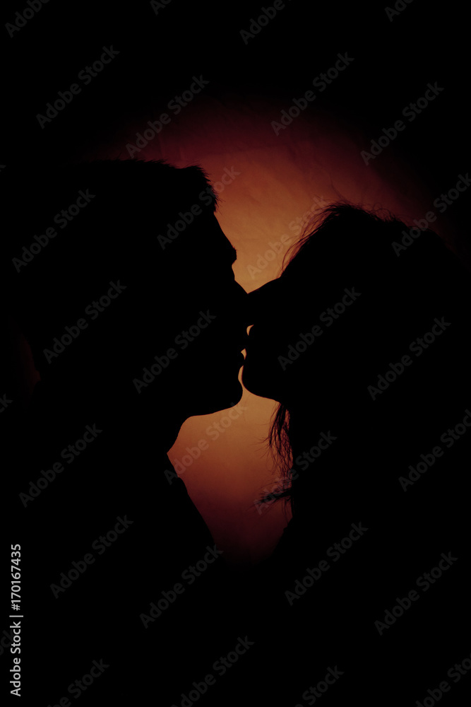 silhouette of two people kissing on a dark background silhouette of two people kissing on a dark background
