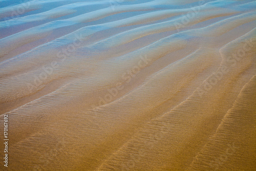 Closeup details of a beach with reflecting blue sky © Tom Nevesely