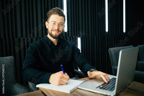 Handsome bearded business man working on project at modern office desk