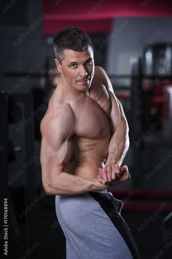 Bodybuilder posing in gym, perfect muscular male body